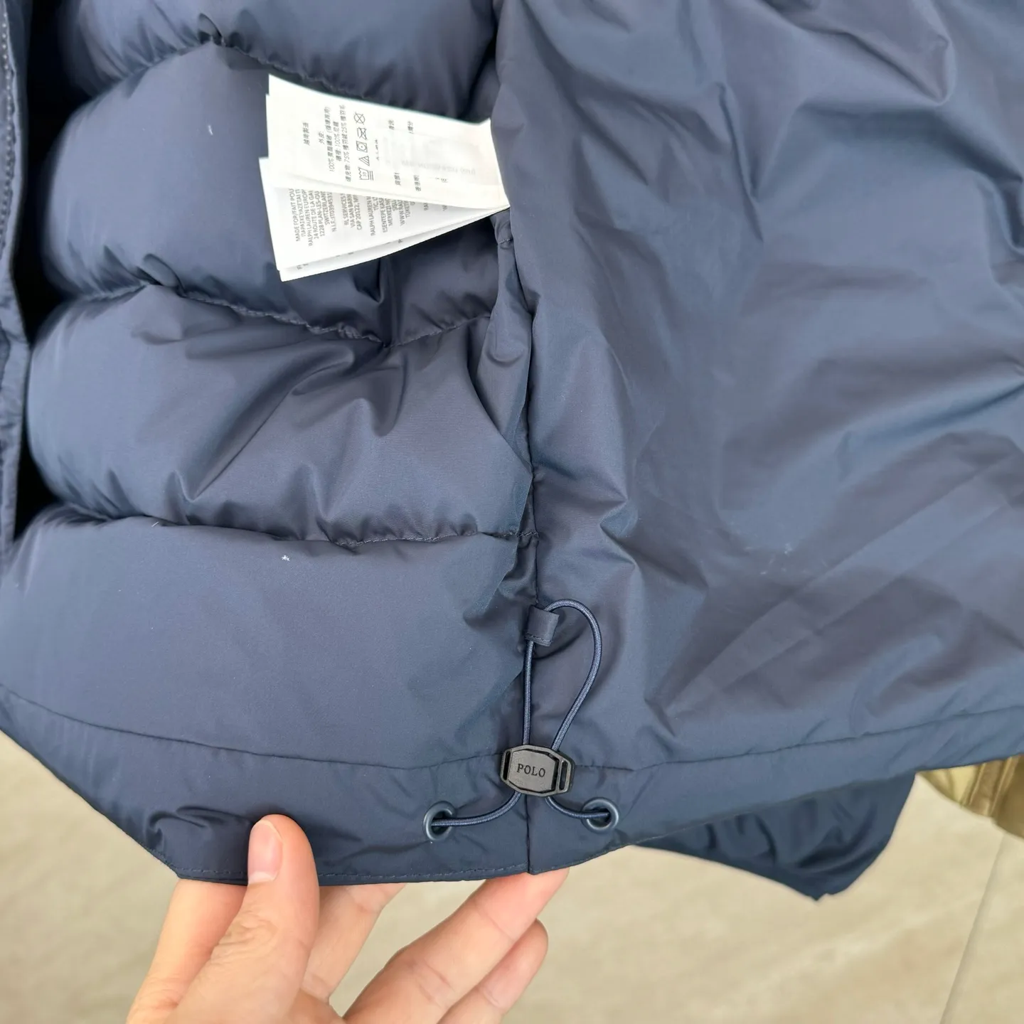 P930 lightweight down jacket size s m l xl Nylon fabric has good windproof and waterproof properties, which can effectively block the intrusion of wind and rain from the outside and keep the inside dry, suitable for wearing in humid or rainy environments.  The red label on the chest is made with an imported MECLO embroidery machine. The original pattern is scanned first, and then high-quality silk thread is used to make a pattern. The density effect is adjusted by continuous pattern making.  Exquisite details: the zipper design is simple and elegant, easy to operate; the closing design of the cuffs and hem effectively prevents the intrusion of cold wind, improving the warmth and comfort of wearing.  High-quality filling: 90 white duck down is selected, with a weight of 260g, ensuring excellent thermal insulation performance. After strict screening and processing, the velvet is not easy to drill, ensuring durability. The hangtags, wash marks, air holes, and four-button buttons are all customized from the original one-to-one mold.